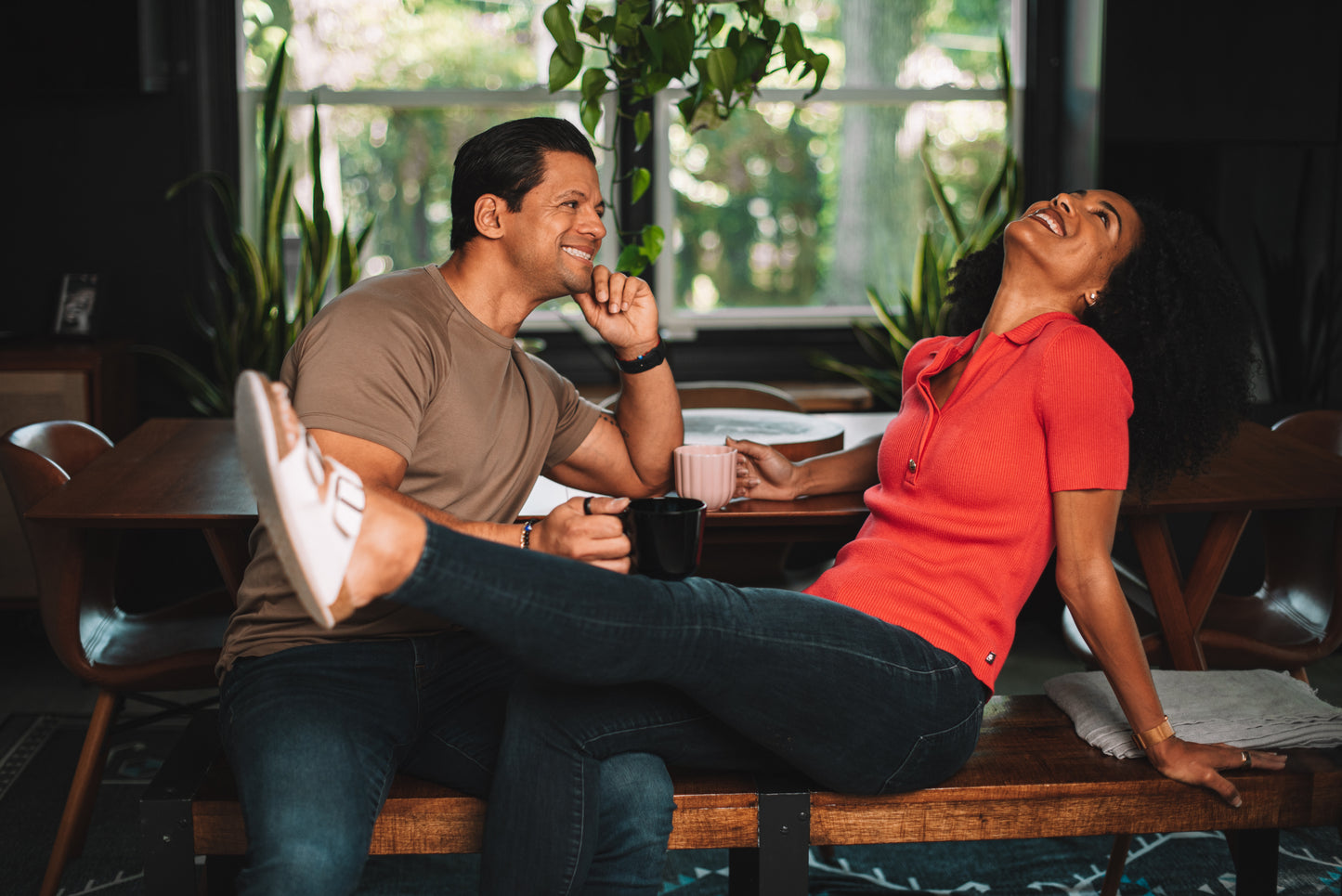 Man and woman sitting on a bench in a cafe, laughing together. Drinking Dancing Ox Coffee